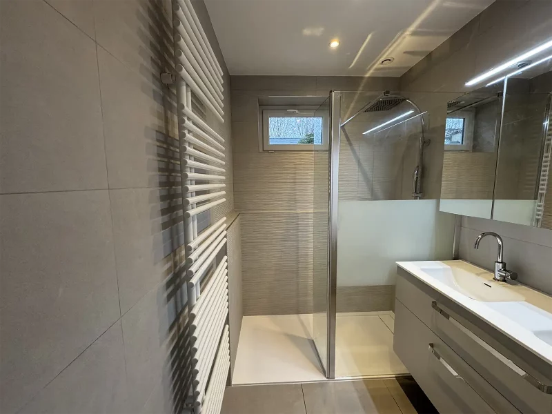 Salle de bains rénovée avec carrelage gris effet pierre au sol et murs, parement imitation marbre, douche à l’italienne, meuble suspendu blanc et robinetterie encastrée inox Saint Michel Sur Orge (91570)