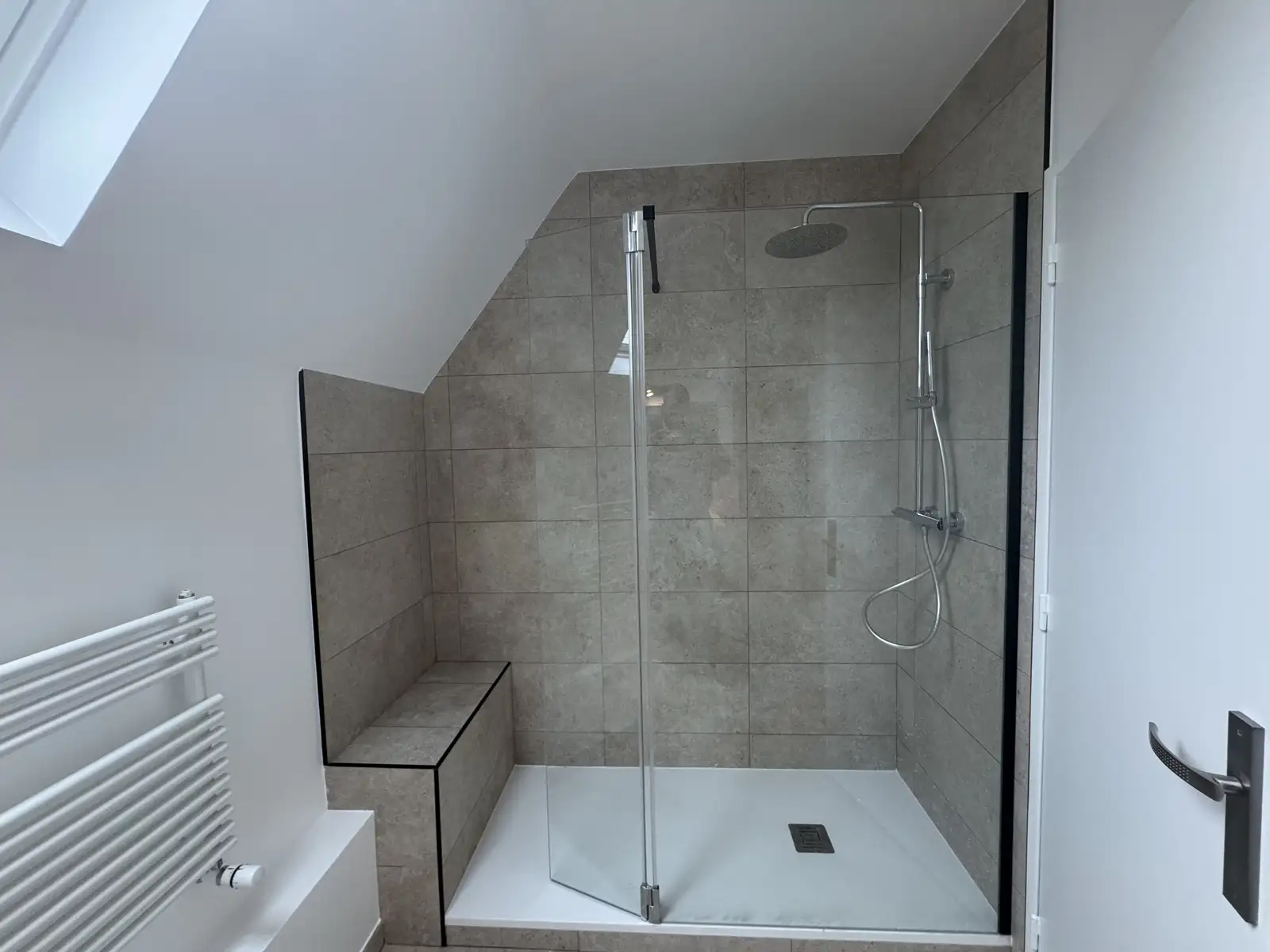 Douche à l’italienne avec carreaux effet pierre et pommeau de douche en inox