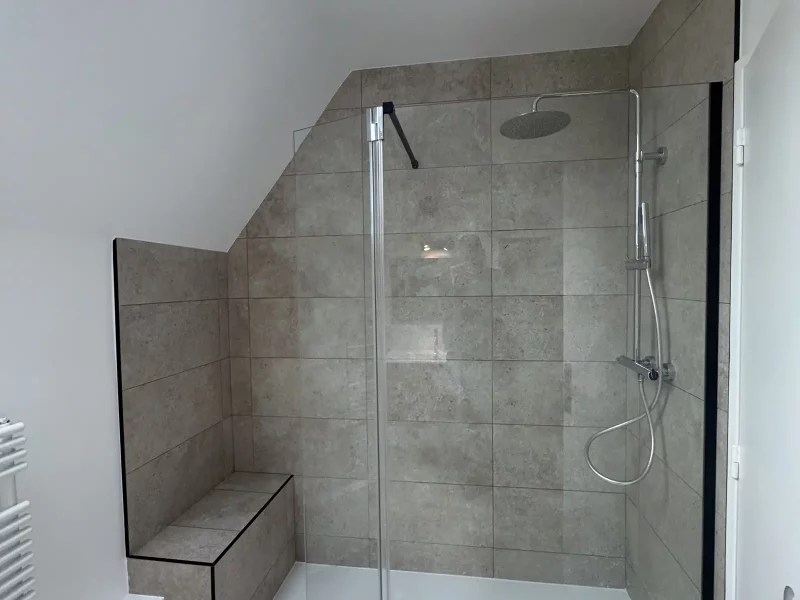 Douche à l’italienne avec carreaux effet pierre et pommeau de douche en inox