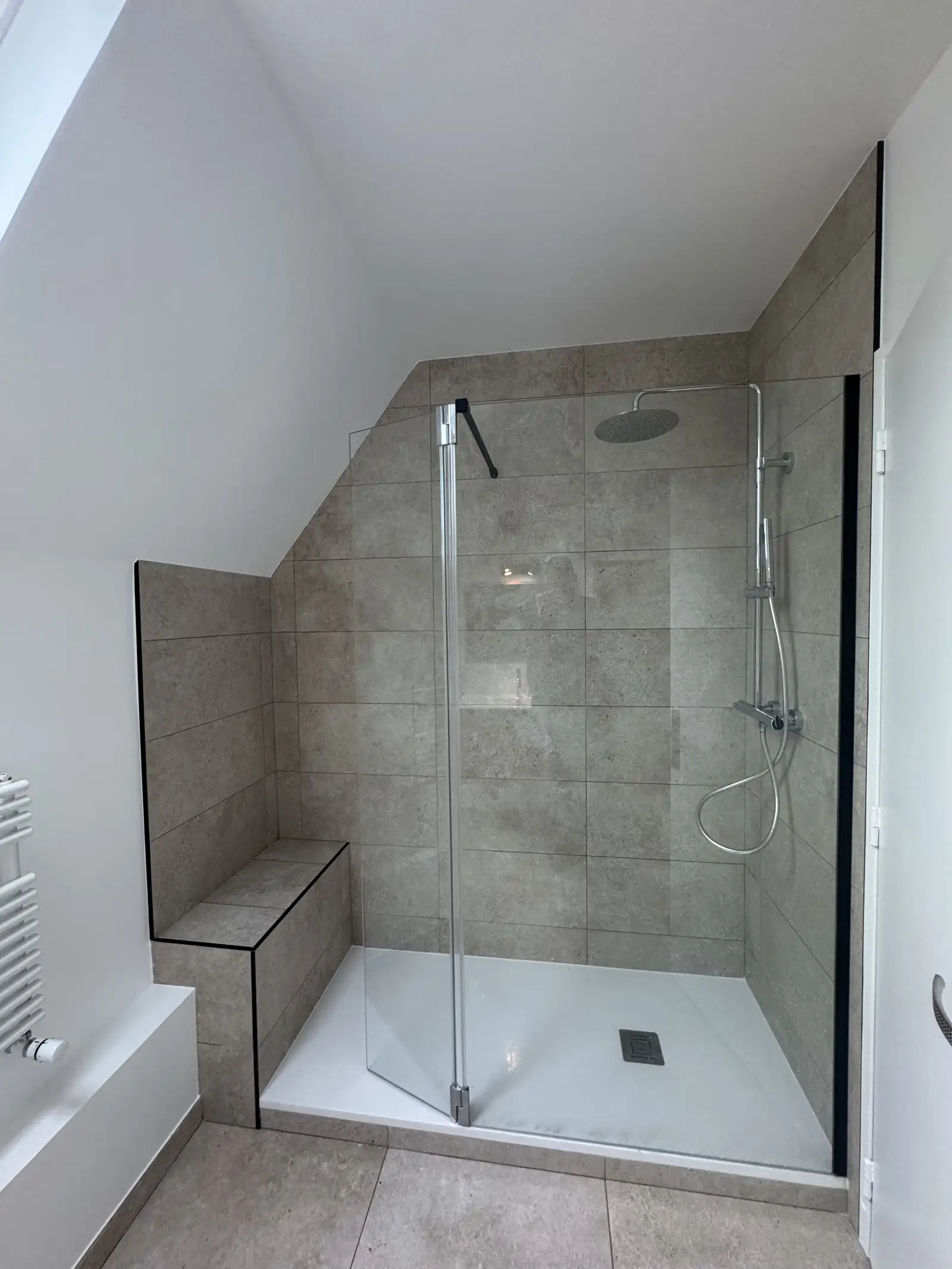 Douche à l’italienne avec carreaux effet pierre et pommeau de douche en inox