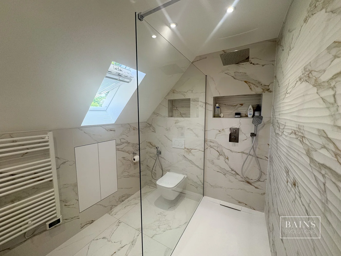 Salle de bains blanc effet marbre élégante à Palaiseau (91) avec douche sous pente verrière et WC suspendu