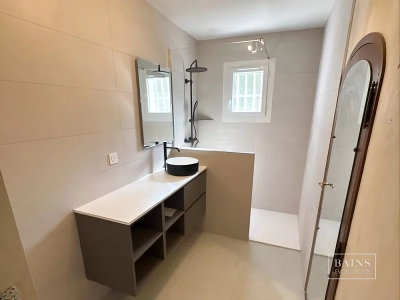 Salle de bains pierre neutre moderne à Montlhéry avec meuble argile, vasque noire et blanche et douche ouverte à Montlhéry (91)