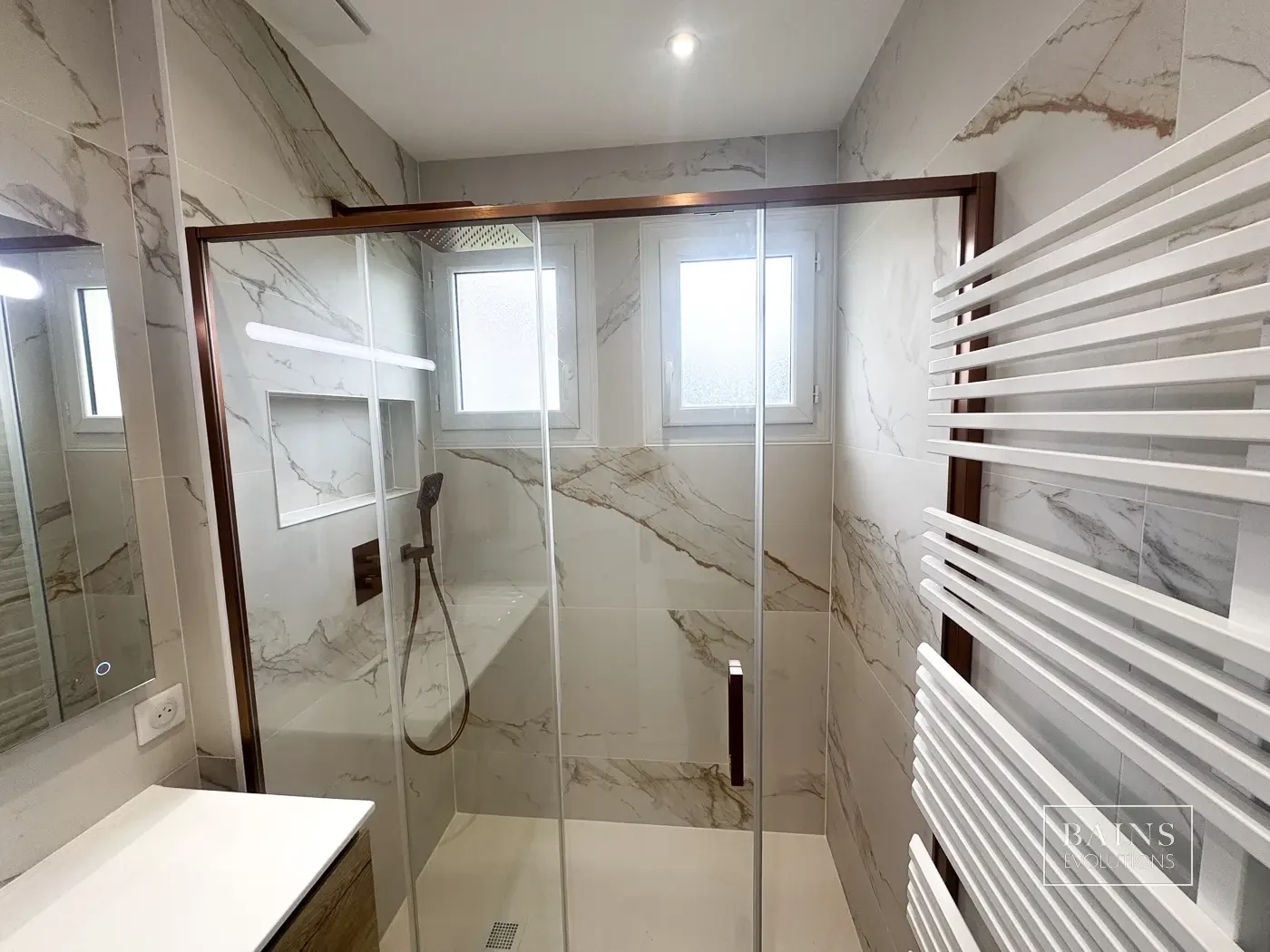 Salle de bains effet marbre gris et doré à Brétigny-sur-Orge avec douche vitrée aux finitions cuivre brossé